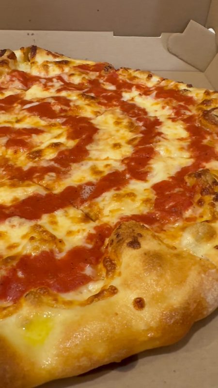 Video still of a cheese pizza with tomato sauce in a takeout box