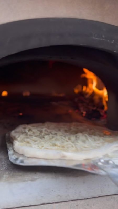 Video still of a pizza being slid into a wood-fired oven